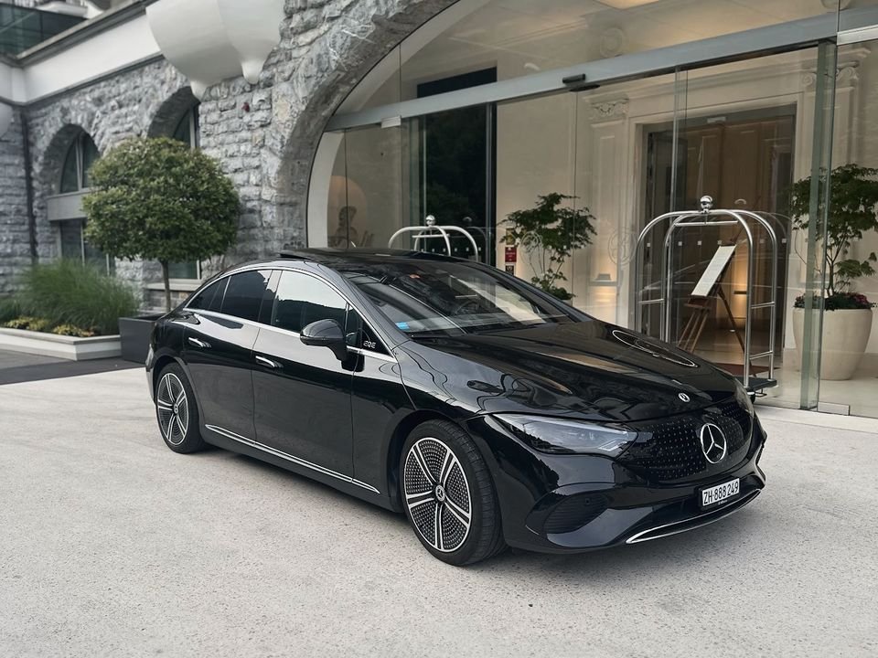 Black Mercedes EQE waiting at a hotel entrance with a stone arch