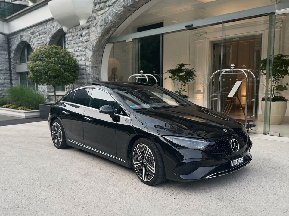 Black Mercedes EQE waiting at a hotel entrance with a stone arch