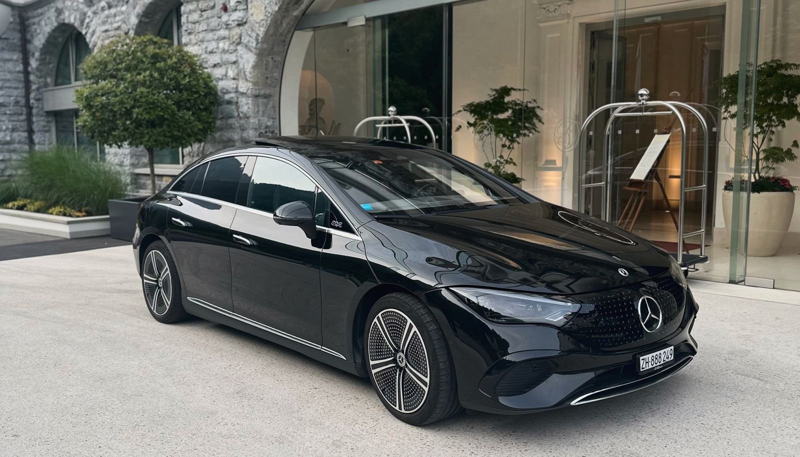 Schwarzer Mercedes EQE wartet vor einem Hoteleingang mit Steinbogen