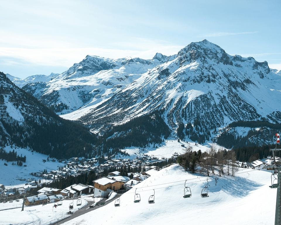 Lech am Arlberg on a sunny winter day: snowy peaks above the village and a chairlift