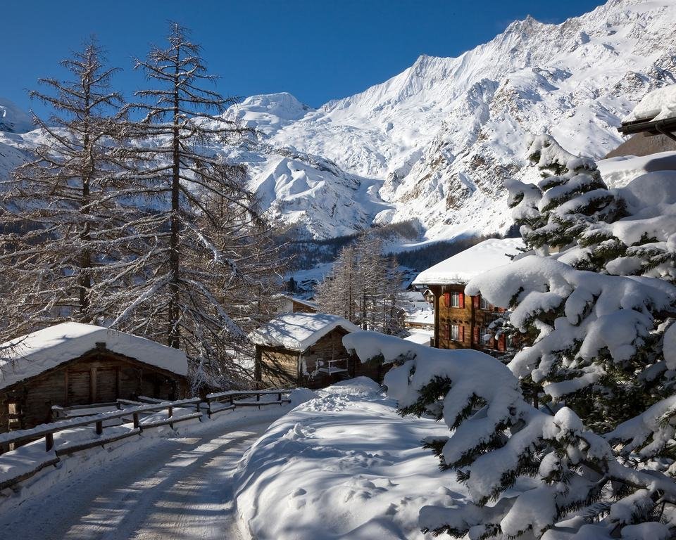 Saas-Fee im Winter: alte Holzstadel und Chalets im tiefen Schnee unter den Gletschergipfeln