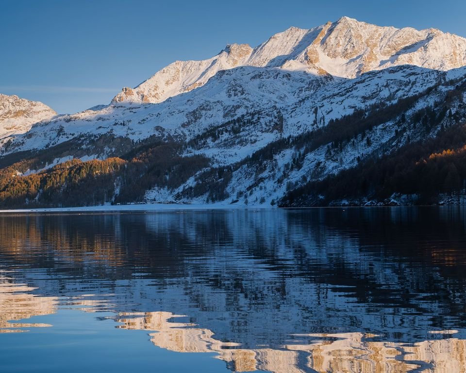 Lake Sils in the Upper Engadine in early winter, snowy peaks reflected in the water