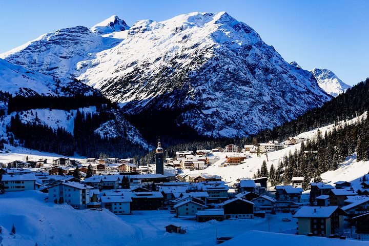 Lech am Arlberg in winter: the village and its church below a snowy mountain