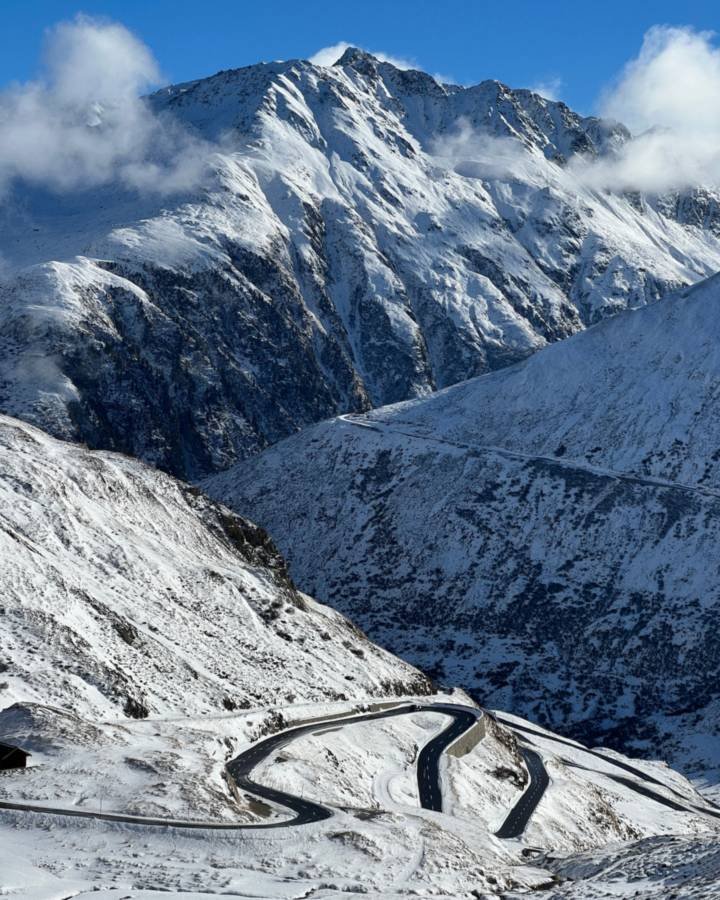 A winding mountain road below snowy peaks in winter
