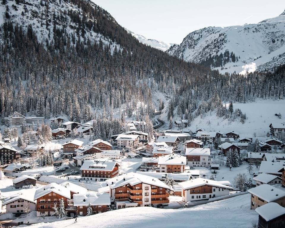 Lech am Arlberg in winter: snow-covered chalets below the forest