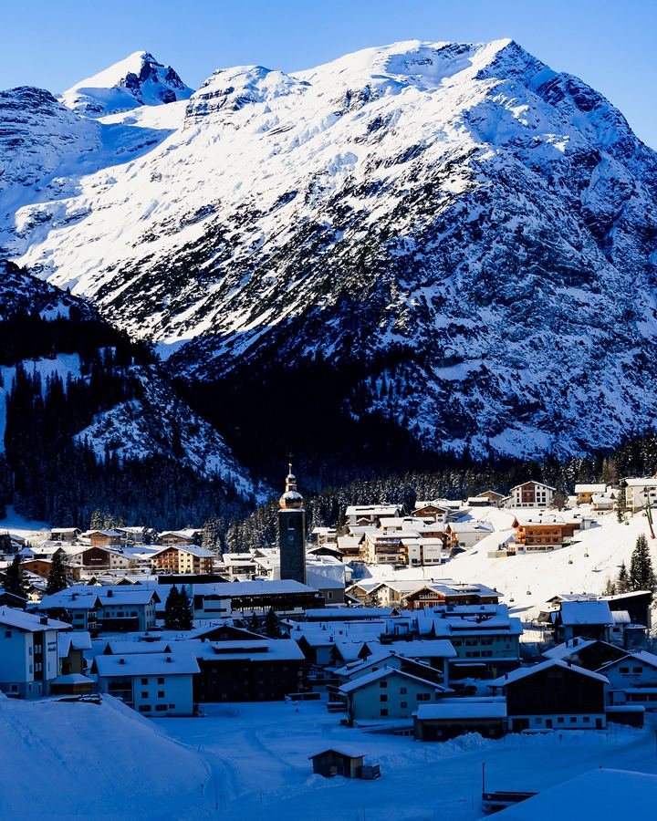 Lech am Arlberg in winter: the village and its church below a snowy mountain