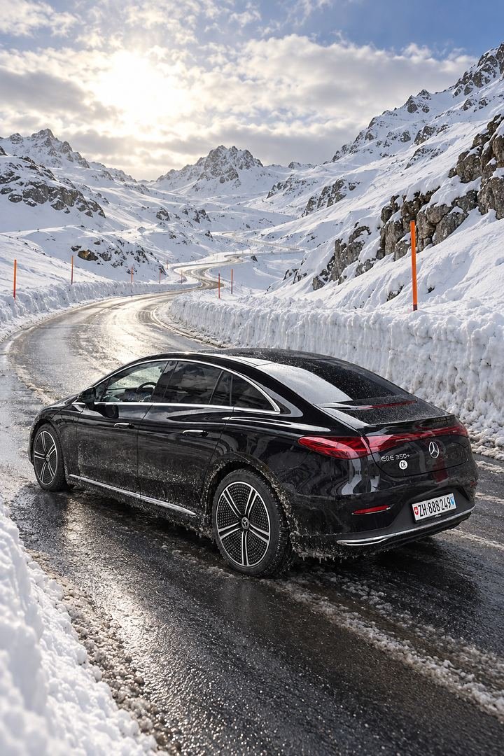 Our black Mercedes EQE on a cleared mountain pass road between walls of snow