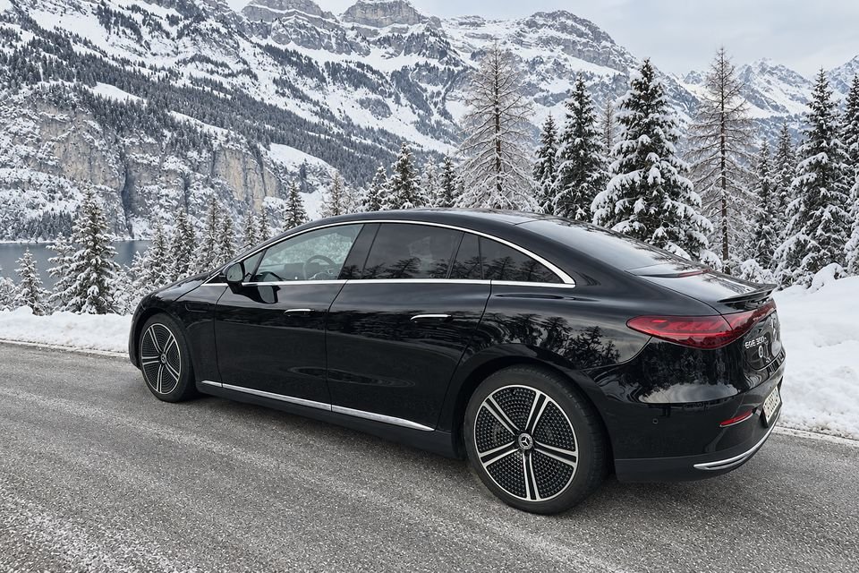 Unser schwarzer Mercedes EQE auf einer geräumten Bergstrasse zwischen verschneiten Tannen