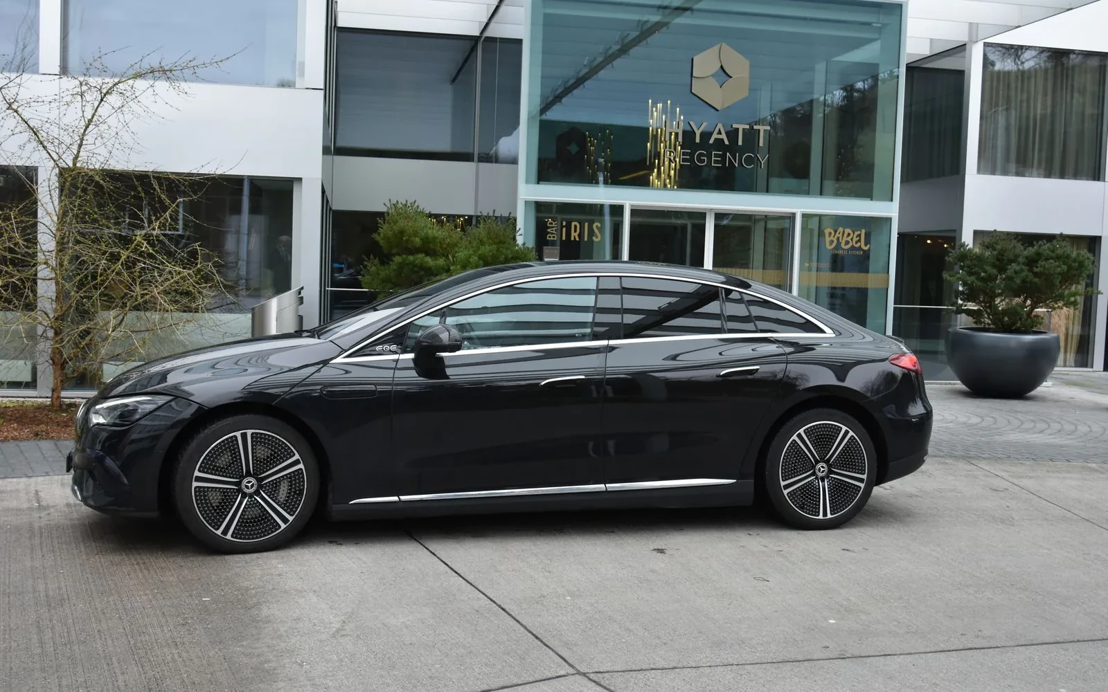 Black Mercedes EQE parked outside a hotel.