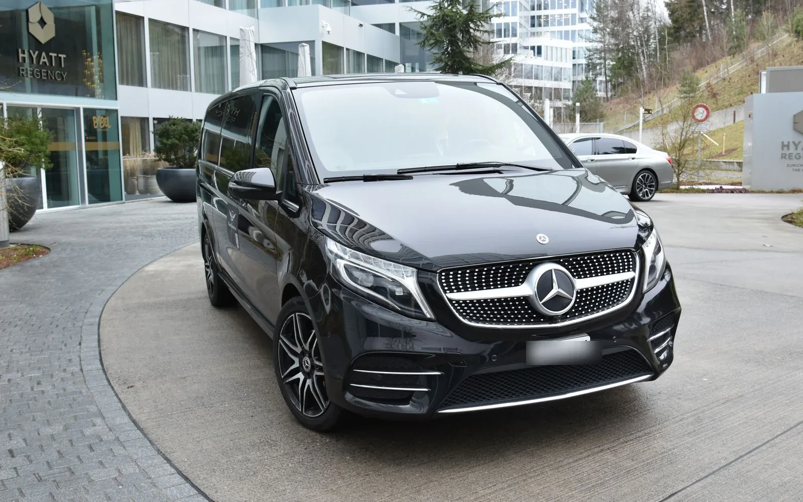 Black Mercedes V-Class parked outside a hotel.