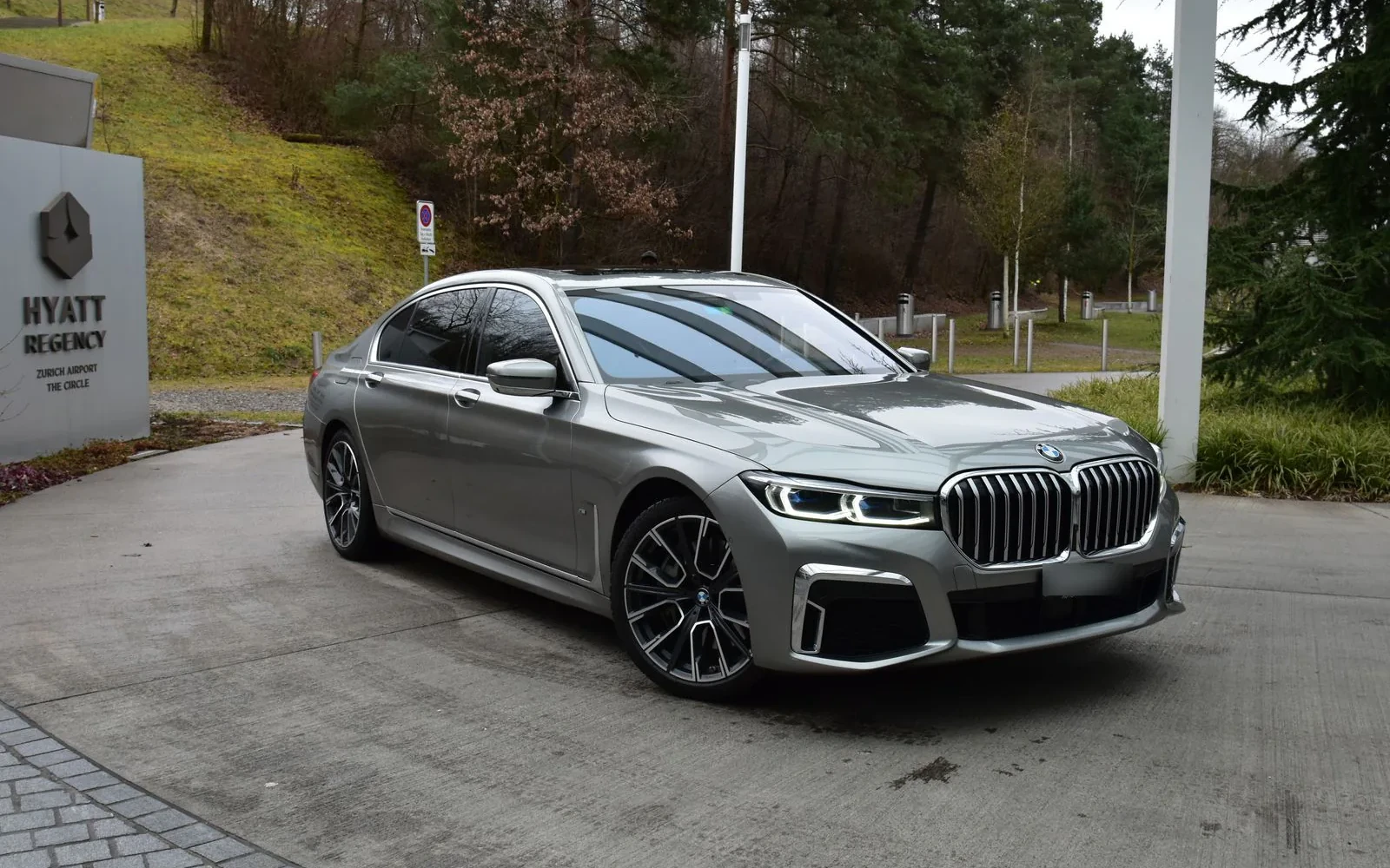 Silver BMW 7 Series parked outside a hotel.