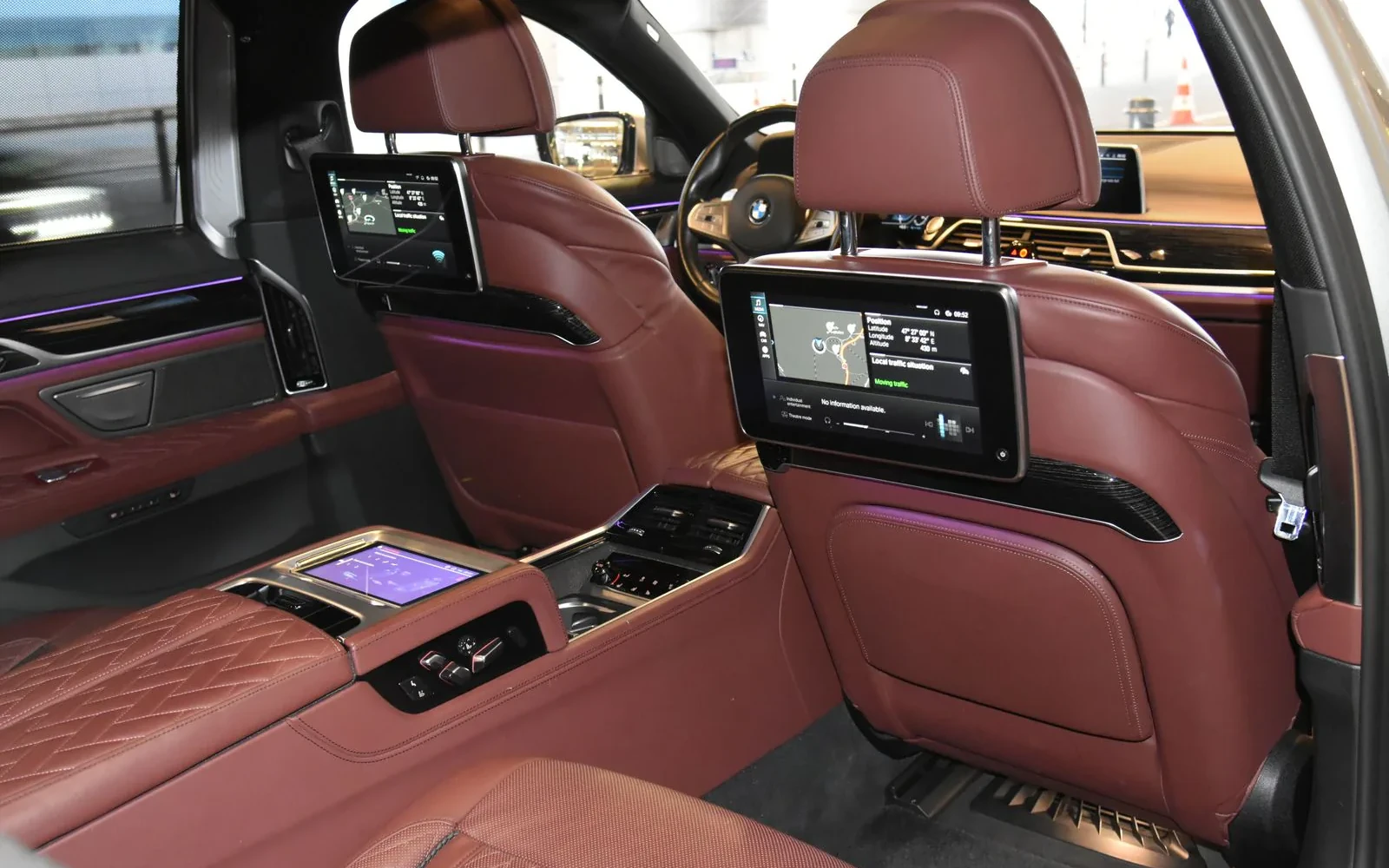 BMW 7 Series rear cabin with red leather seats and screens.