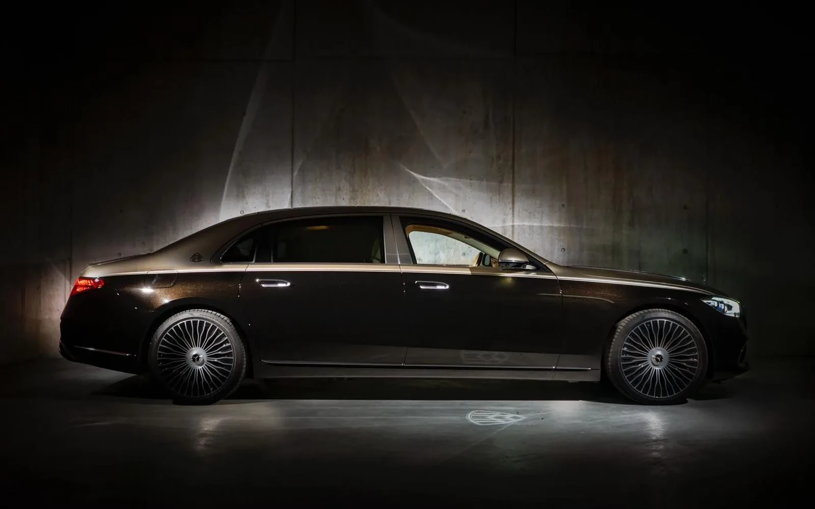 Black Mercedes-Maybach sedan in a dark studio setting.