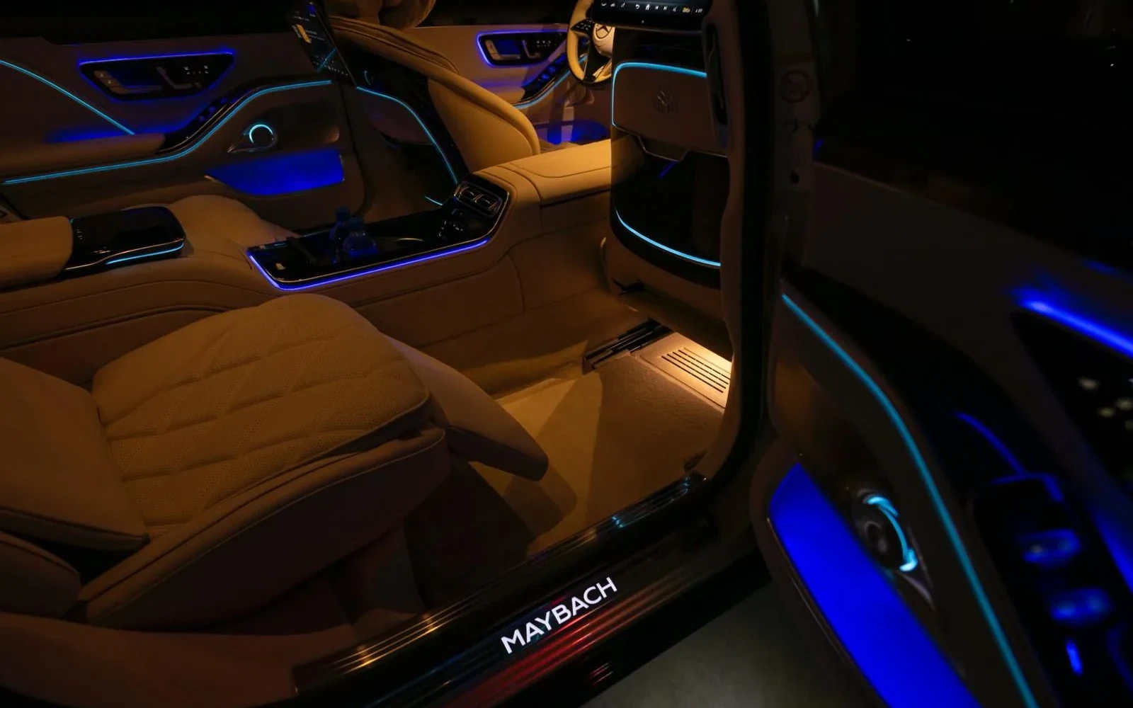 Mercedes-Maybach rear cabin with tan seats and blue ambient lighting.