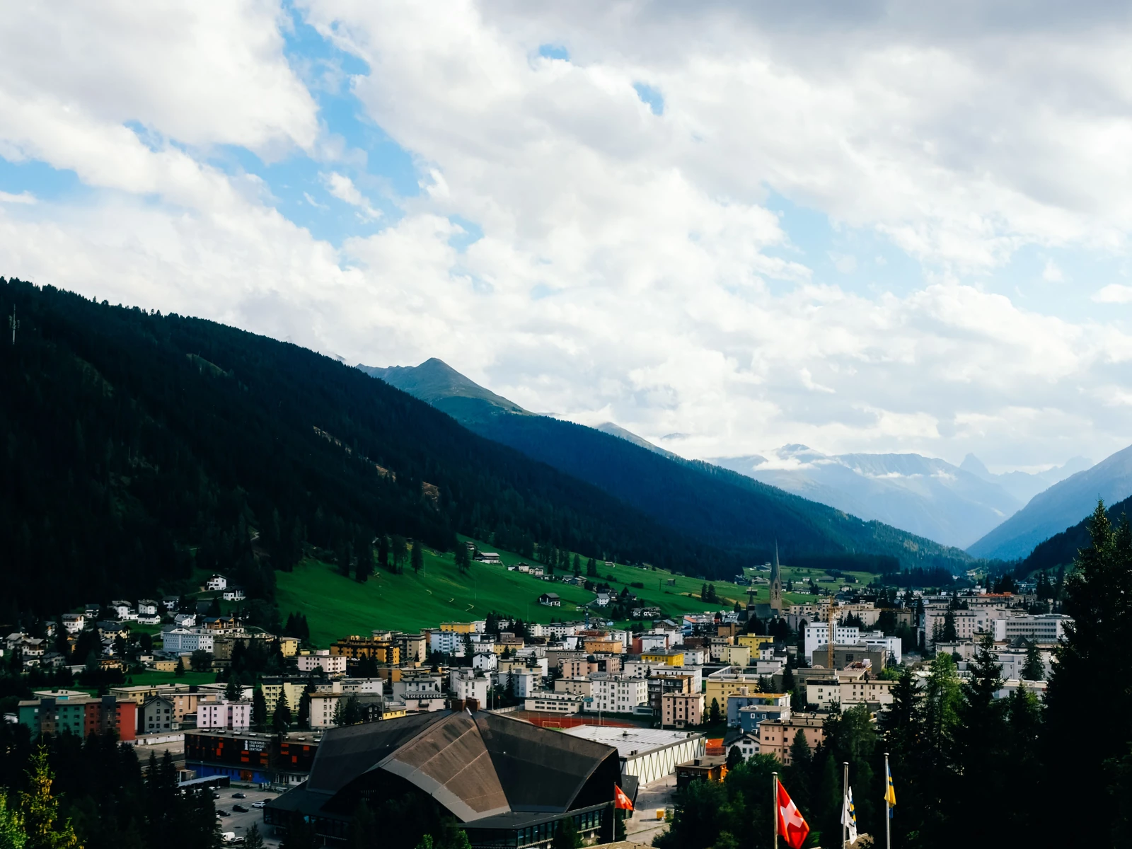 Davos in a green Alpine valley beneath a bright, clouded sky.